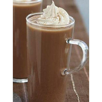 Une tasse transparente d’une boisson brune avec de la chantilly saupoudrée de cacao, sur une table avec une nappe brune