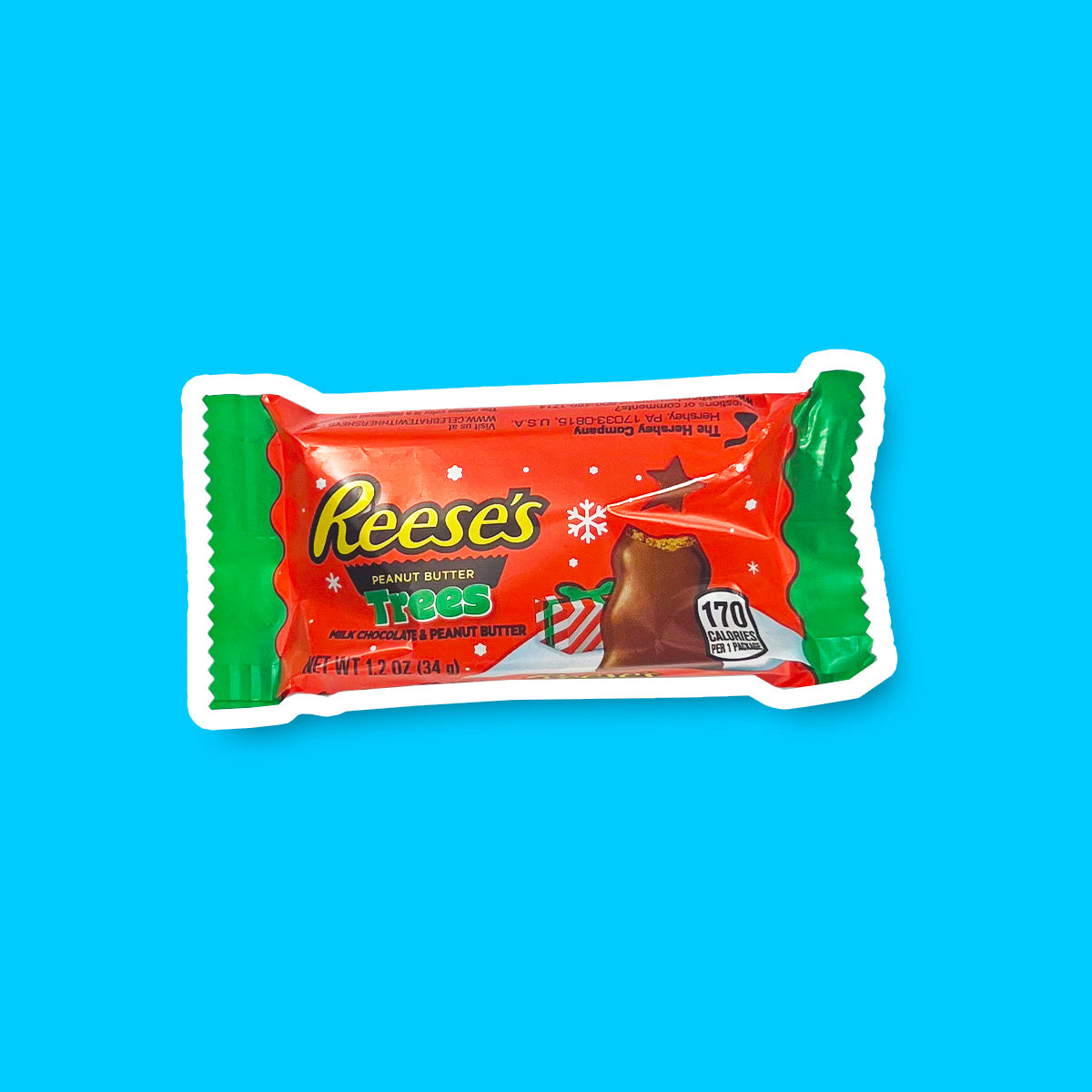 Un emballage orange sur fond bleu, avec des extrémités vertes. Il y a un chocolat croqué en forme de sapin devant un tas de neige et un cadeau rouge et blanc