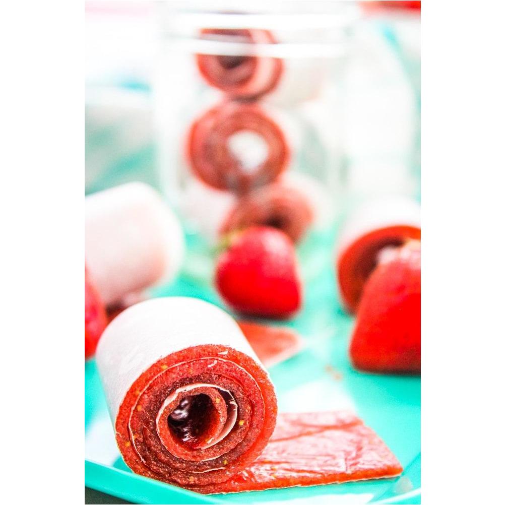 Un bonbon rouge enroulé et derrière des brochettes de 3 bonbons enroulés avec une fraise devant, le tout dans un plastique bleu