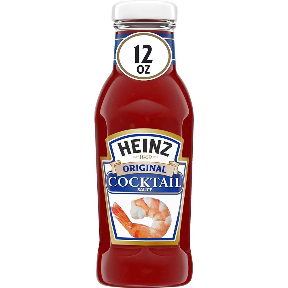 Une bouteille en verre transparent d’une sauce rouge, un capuchon blanc et une étiquette blanche au centre avec une crevette rose. Le tout sur fond blanc