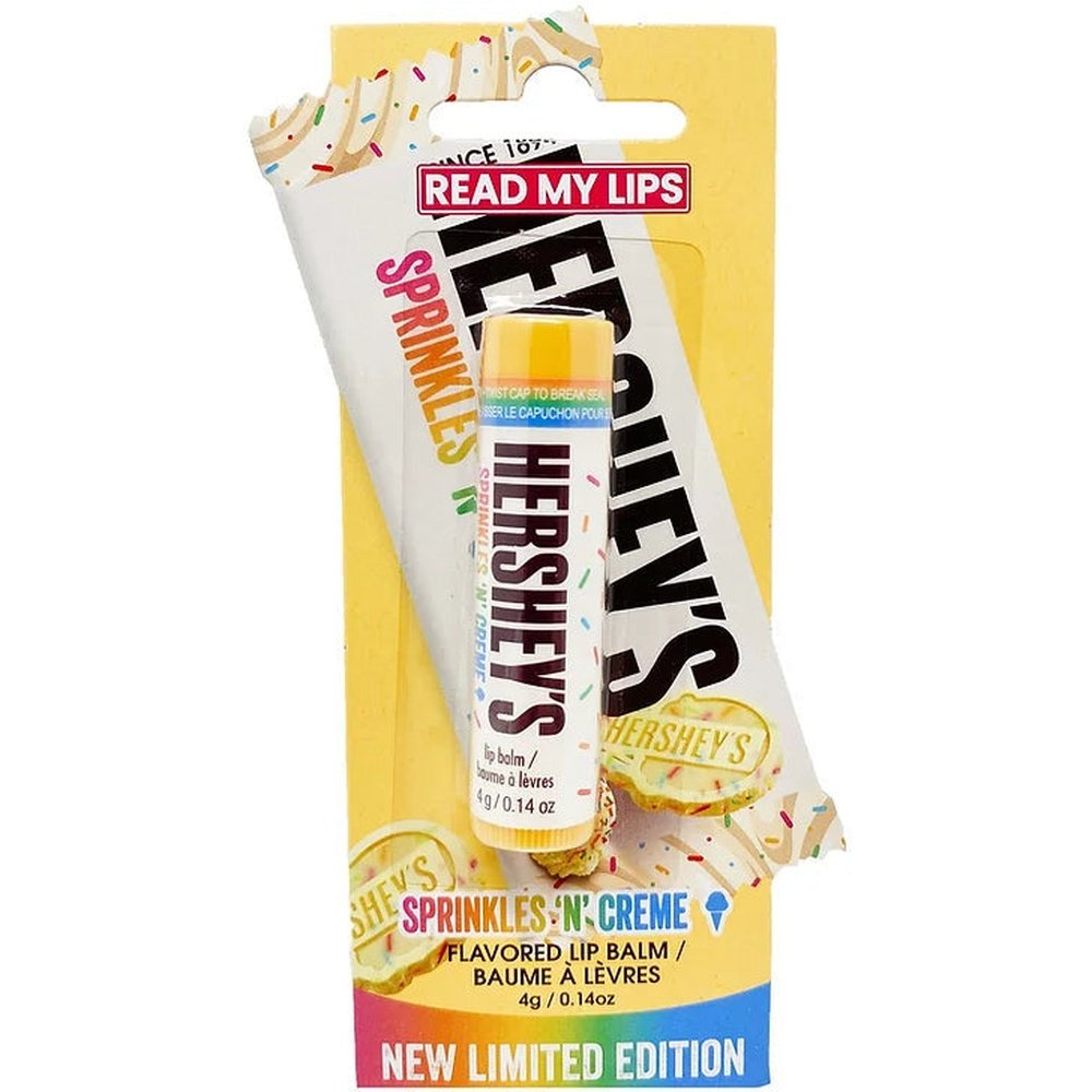 Un emballage jaune sur fond blanc avec un plastique transparent qui montre un baume à lèvre blanc avec des vermicelles multicolores