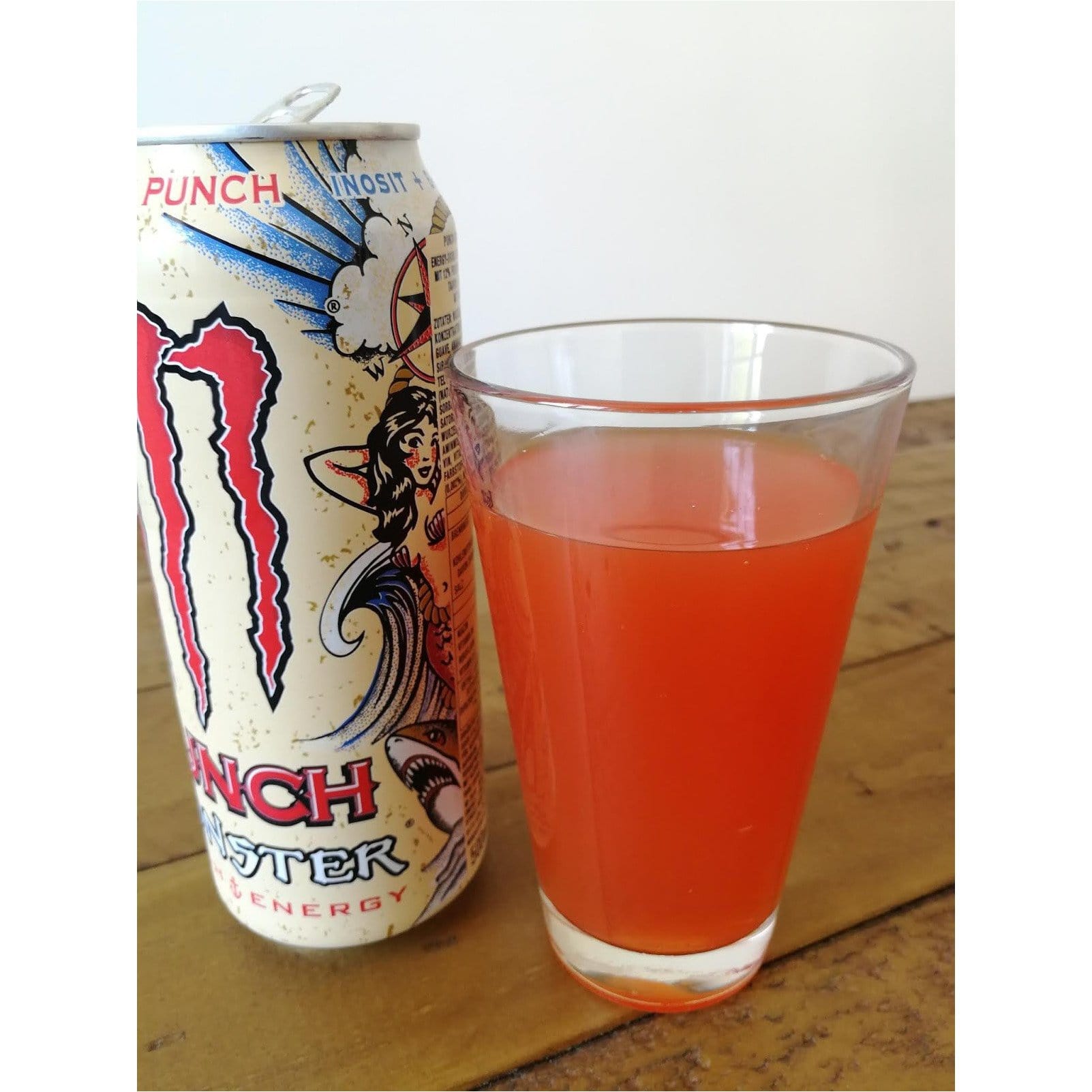 Une canette beige sur fond blanc avec au centre le logo rouge de Monster, un grand M. Sur le côté un verre de Monster Pacific Punch