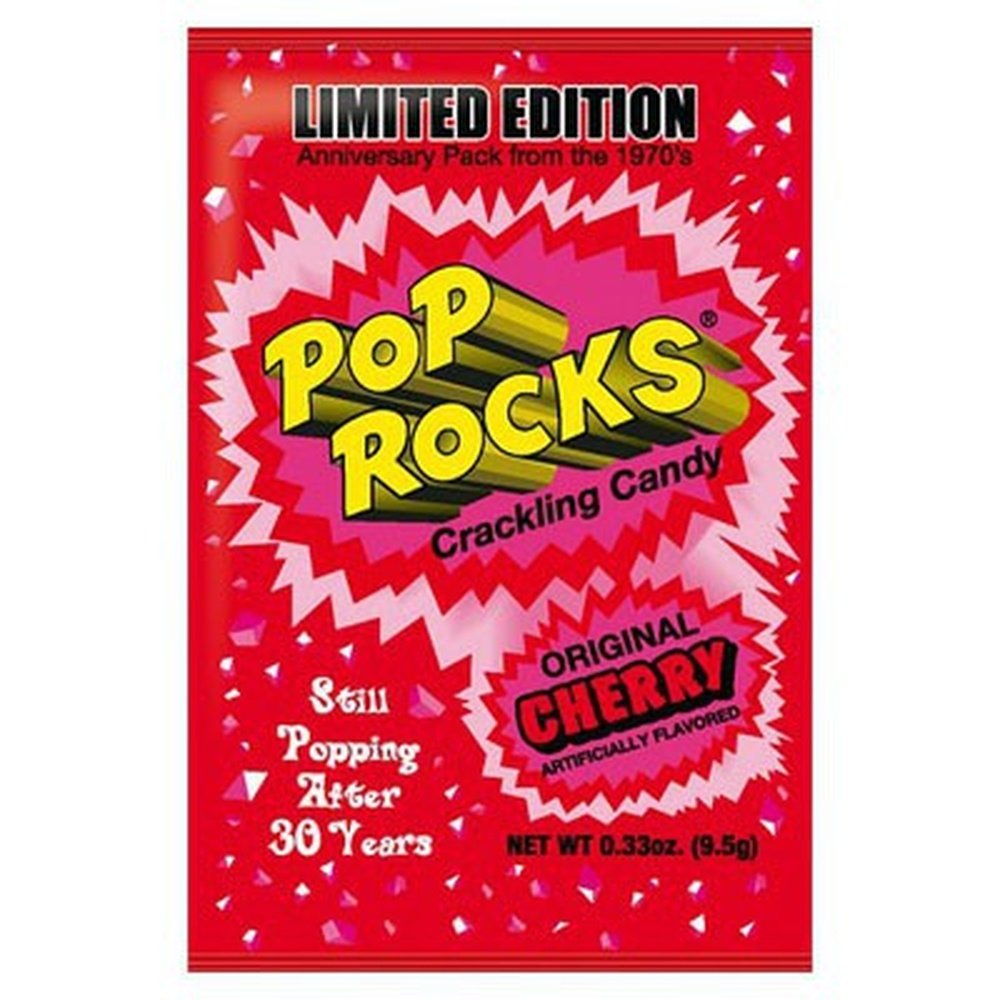 Un emballage rouge avec des petites confettis blanches et roses, le tout sur fond blanc et au centre il est écrit « Pop Rocks » jaune