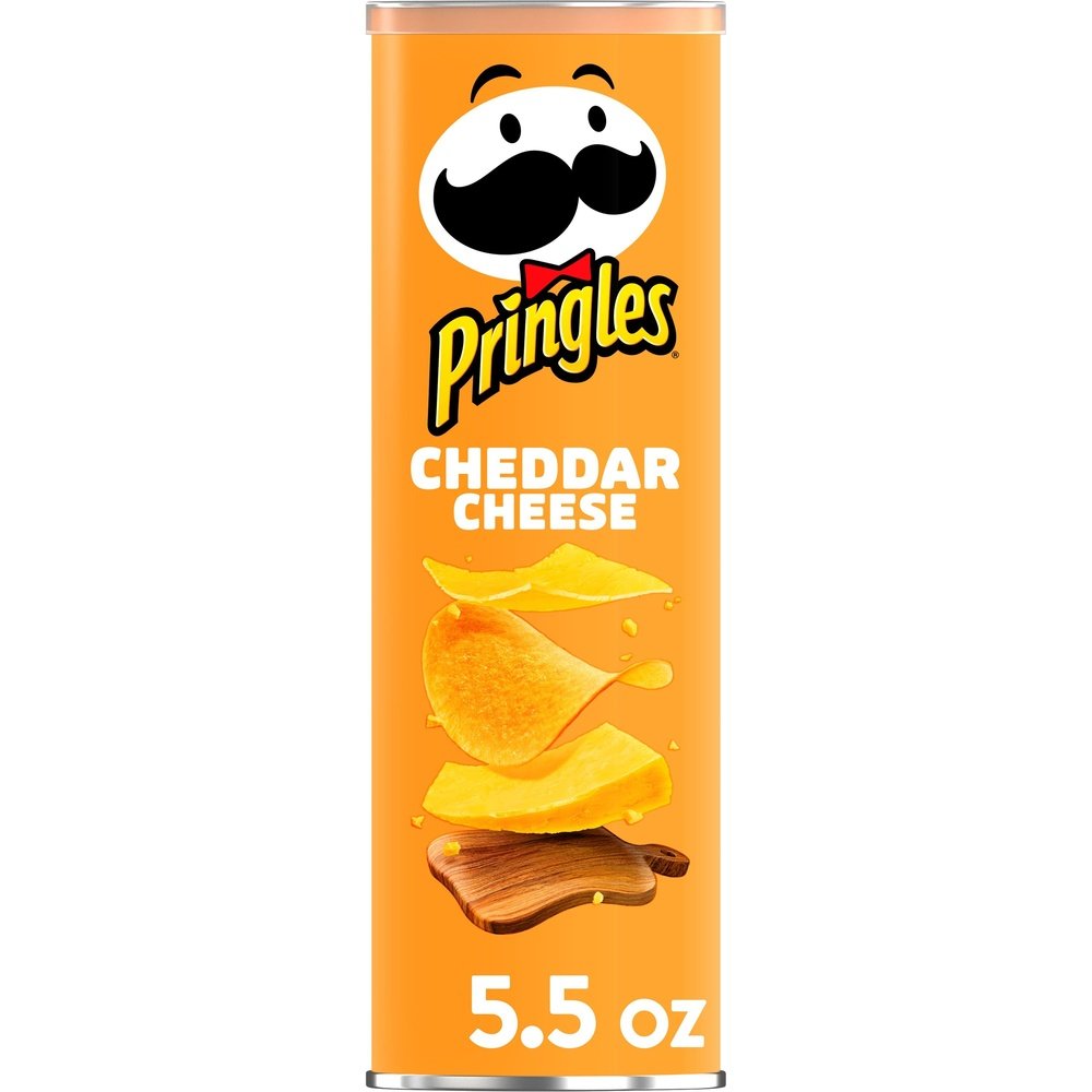 Un paquet en forme de cylindre orange, au milieu il y a une planche en bois et au-dessus une chips entre 2 tranches de fromage différents. Le tout sur fond blanc