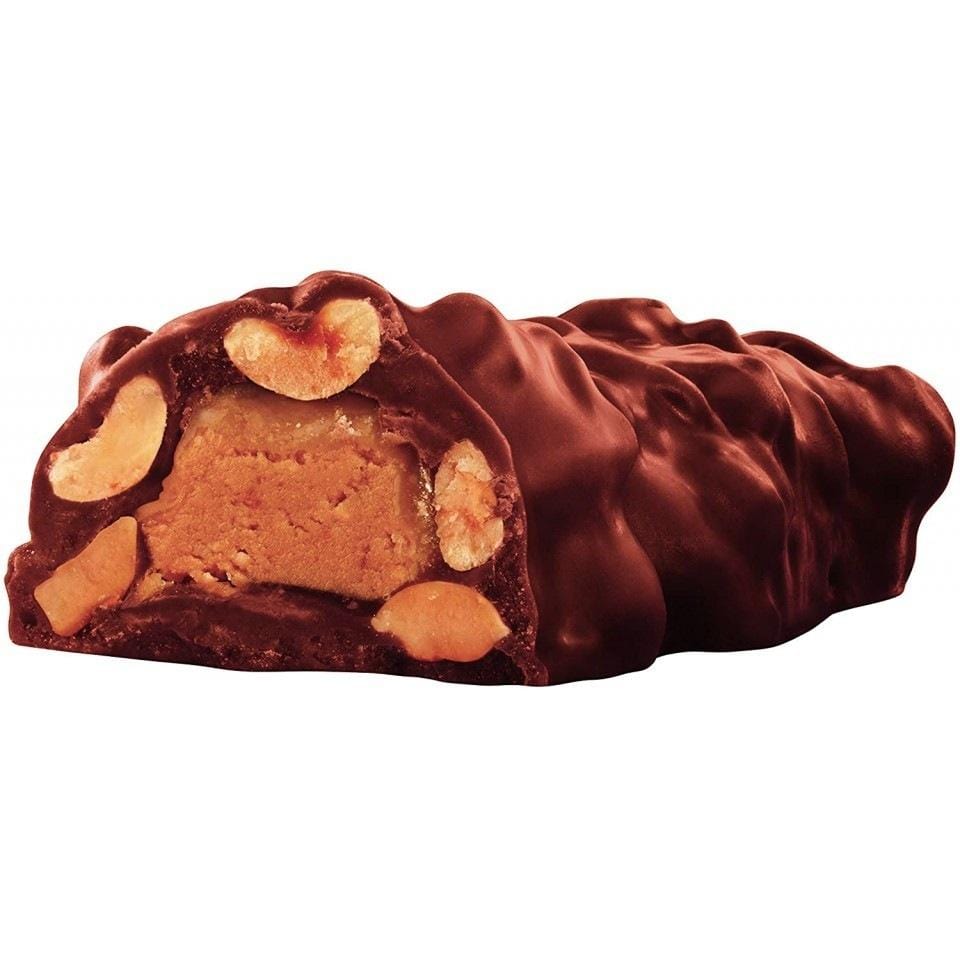 Une barre de chocolat coupé, il y a à l’intérieur du beurre de cacahuètes, caramel et des cacahuètes. Le tout sur fond blanc